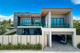 The Arowanyx modern house exterior at dusk with a swimming pool, integrated garage, and two cars.