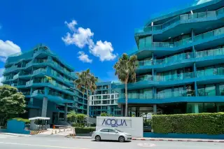 Acqua Condo: Aerial view of blue modern buildings surrounding a long, winding swimming pool with integrated islands and bridges.