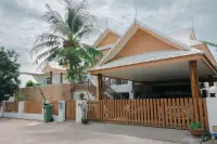 6 Bedroom House for Sale & Rent at Amorn Village, exterior view with carport, wooden fence, and palm tree.