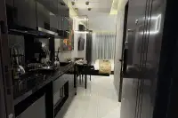 Studio Condo for Sale at Grand Solaire Noble open-plan interior with black kitchen, dining table, and bed area on marble floors
