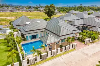 Baan Dusit Pattaya Hill 5: Aerial view of a house with a blue swimming pool, green lawn, and other houses in the background.