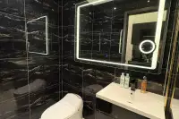 Studio Condo for Sale at Grand Solaire Noble luxury bathroom with black marble walls, large LED backlit mirror, white vanity, and smart toilet