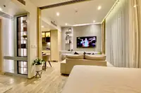 1 Bedroom Condo for Sale & Rent at Arom Wongamat: Open-plan living area with bed, sofa, TV, and view into kitchen/dining.
