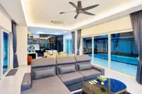 3 Bedroom House for Sale in Nong Prue open-plan living room with grey L-shaped sofa, pool view, dining area and modern kitchen
