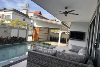 Zensiri Midtown Villas covered outdoor terrace with rattan sofa, poolside ceiling fan, wall-mounted TV and wooden entry gate