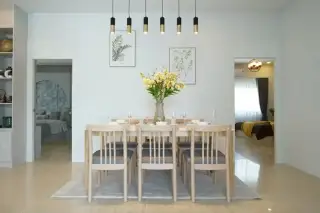 Phonthep Garden Ville 2 dining room with large wooden table, pendant lights, botanical wall art, and views to bedrooms