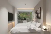 2 Bedroom Condo for Sale at Celine Wongamat bedroom with king bed, wood panel headboard, built-in desk, and lush garden view