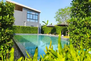 Supalai Palm Ville Sukhumvit - Rongpo outdoor swimming pool with lounge chairs and modern gray building surrounded by green foliage.