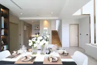 4 Bedroom House for Sale at Highbury Hill Pool Villas Pattaya formal dining table with white floral centrepiece and wooden staircase