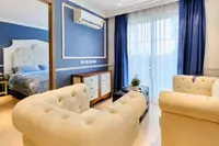 2 Bedroom Condo for Sale at Seven Seas Cote d'Azur: living room with cream armchairs, blue curtains, and bedroom entrance.