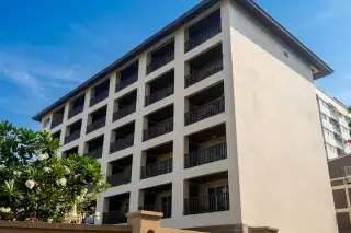 Katalina Residence exterior, showing multiple floors of balconies with dark railings, light facade, and a low wall.