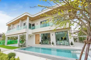 Perla Villa: Modern white house with a swimming pool, large glass doors, and balconies, under a blue sky.