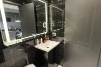 1 Bedroom Condo for Sale at Zenith Pattaya modern bathroom with black marble tiles, LED backlit mirror, and white basin