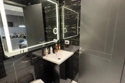 1 Bedroom Condo for Sale at Zenith Pattaya bathroom with black marble walls and illuminated vanity mirror