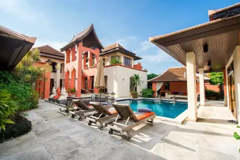 Phutara outdoor swimming pool area with sun loungers, surrounded by multi-story houses and lush greenery.