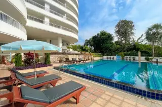 Baan Rimpha large curved swimming pool with ocean view, sun loungers, and white buildings on a sunny day.