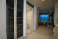 Studio Condo for Sale at SKYPARK Lucean Jomtien Pattaya: Entryway with glass-front cabinet, bathroom, and view into bedroom.