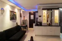 2 Bedroom Condo for Rent at Wongamat Privacy open-plan living area with black sofa, blue LED ceiling lighting and white kitchen counter