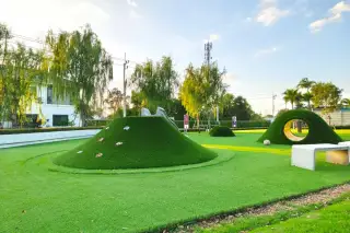 Supalai Palm Ville Sukhumvit - Rongpo outdoor children's playground with green artificial turf mounds, slides, and tunnels.