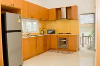 6 Bedroom House for Sale & Rent at Amorn Village, kitchen with wooden cabinets, yellow tiled backsplash, and appliances.