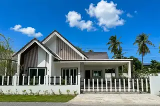 Coco Ville by Sabai Home: Modern white house exterior with black roof, fence, gate, and palm trees under a blue sky.