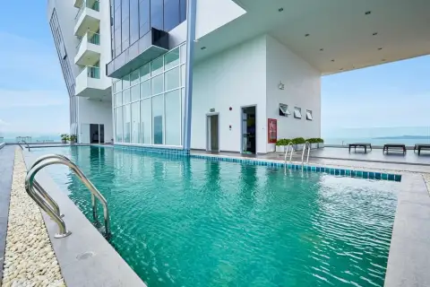 The Vision: Rooftop swimming pool with blue tiles, surrounded by a building facade and distant ocean views.
