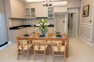 SP Village 1 kitchen and dining area with wood cabinets, black countertops, and 6-seat wooden dining table with wishbone chairs