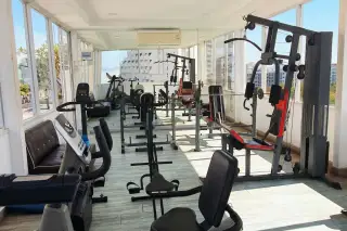 Serenity Wongamat fitness center with various exercise machines, large windows, and city views.