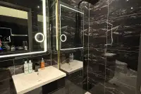 Studio Condo for Sale at Grand Solaire Noble bathroom with black marble walls, glass walk-in shower, and dual white sinks