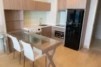 1 Bedroom Condo for Sale at Cetus Beachfront modern kitchen with wood cabinets, white countertop, dining table, and black refrigerator