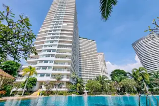 View Talay 7 high-rise condo tower with palm trees and outdoor pool in foreground, Pattaya