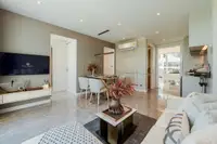 2 Bedroom Condo for Sale at The Coral Pattaya: living area with TV, dining table, and view into the kitchen from sofa.