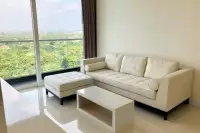 2 Bedroom Condo for Sale at Del Mare living area with cream sofa set and floor-to-ceiling window overlooking green treetops