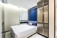 2 Bedroom Condo for Sale at Embassy Life, second bedroom with white bed, blue headboard, and built-in wardrobe.