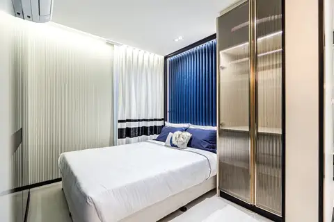 2 Bedroom Condo for Sale at Embassy Life, second bedroom with white bed, blue headboard, and built-in wardrobe.