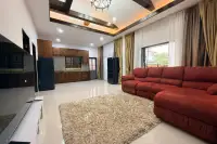 3 Bedroom House for Sale at Baan Dusit Pattaya Park living room with red sofa, rug, and kitchen in background.