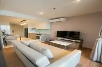 1 Bedroom Condo for Rent at Once Pattaya spacious living room with large sofa, flat-screen TV, open kitchen, and wood flooring