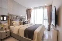 1 Bedroom Condo for Sale at Copacabana Coral Reef master bedroom with tall padded headboard, wall TV and floor-to-ceiling curtains