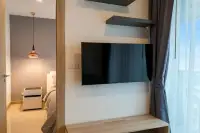 1 Bedroom Condo for Rent at The Riviera Jomtien wall-mounted flat-screen TV with floating shelves and bedroom doorway view