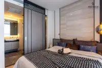 Studio Condo for Sale at Andromeda Condominium bedroom with double bed, stone-clad feature wall, pendant lamp, and en-suite bathroom entry