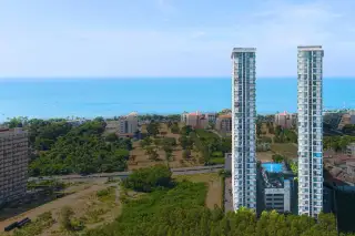 The Twin Tower Jomtien Beach Pattaya drone aerial view of twin towers with rooftop pool surrounded by green trees and Jomtien Beach sea