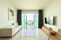 1 Bedroom Condo for Rent at Movenpick Residences living room with white sofa, TV, and balcony with ocean view.