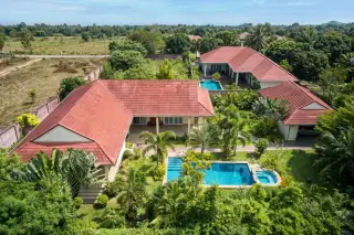 Sundance Villas aerial view of multiple houses with red tiled roofs, lush green gardens, and two swimming pools.