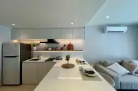 1 Bedroom Condo for Sale at Celine Wongamat kitchen with white countertop island, under-cabinet lighting, fridge, and grey sofa