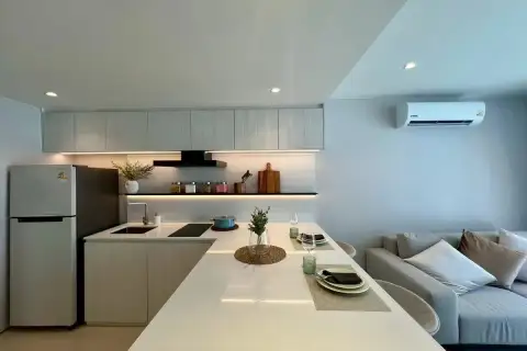 1 Bedroom Condo for Sale at Celine Wongamat kitchen with white countertop island, under-cabinet lighting, fridge, and grey sofa
