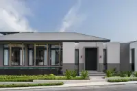 4 Bedroom House for Sale at Cascade front facade close-up showing black entry door, gold-trimmed columns, floor-to-ceiling glazing, and tropical landscaping