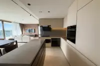3 Bedroom Condo for Rent at Panora Estuaria modern open-plan kitchen with large island, built-in induction hob, oven and cream cabinetry