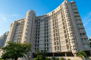 Peak Condominium, exterior view of the large, curved, grey condominium building with multiple windows and balconies.