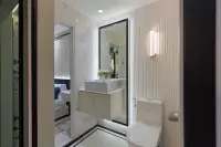 1 Bedroom Condo for Sale at Embassy Life en-suite bathroom with marble walls, vessel sink vanity, large mirror, and toilet