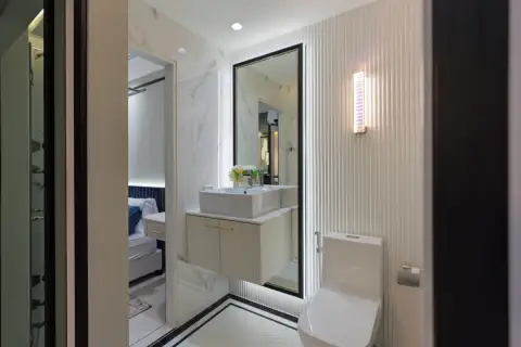 1 Bedroom Condo for Sale at Embassy Life en-suite bathroom with marble walls, vessel sink vanity, large mirror, and toilet